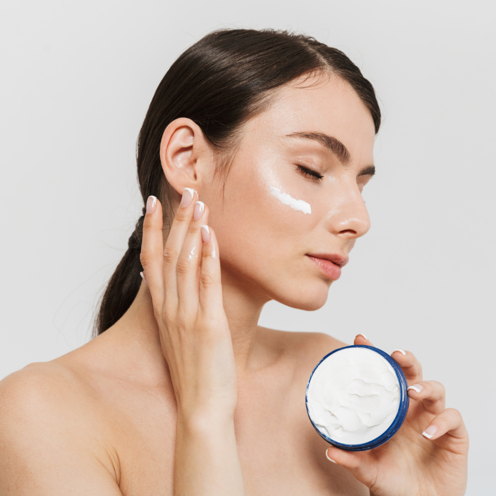 Woman applying cosmetic cream lotion to her face